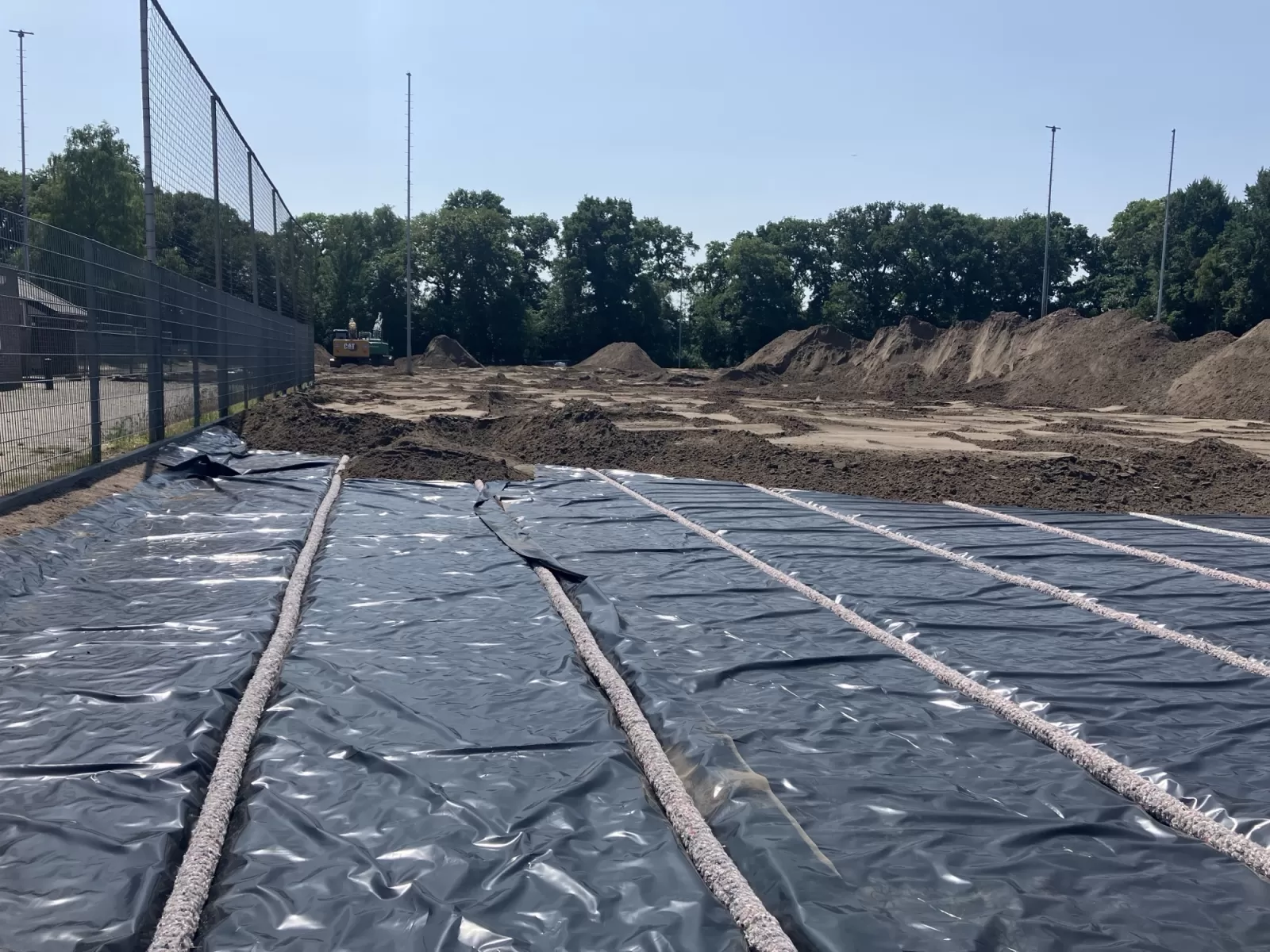 Opengelegd sportveld met drainage en in de verte bedekt met zand 