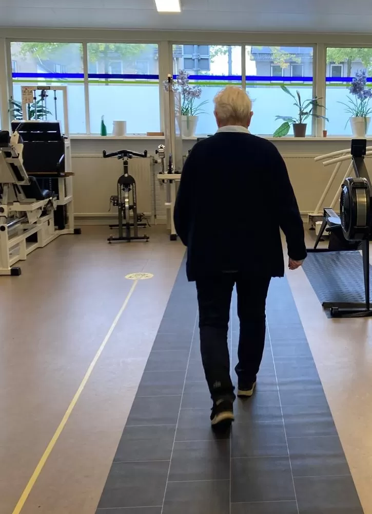 Inwoner loopt over de Smartfloor; een slimme mat die het looppatroon analyseert en een mogelijk valrisico detecteert.